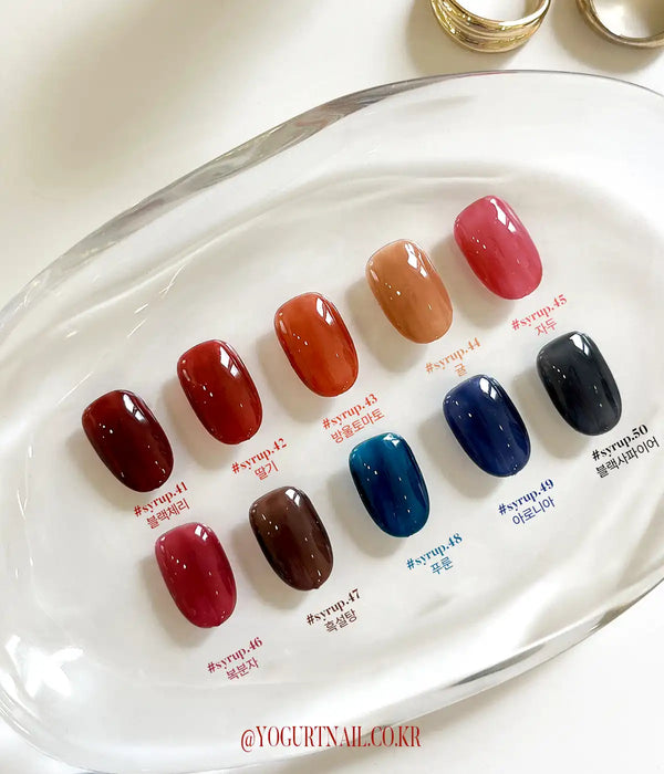 Vivid and lush nail polish colors in the Yogurt Tanghulu Collection, showcased on a glass plate, offering a range of deep, self-levelling syrup shades reminiscent of the candied fruit, Tanghulu. The collection features a variety of single gel options, allowing customers to find the perfect color by checking the swatch card and number.