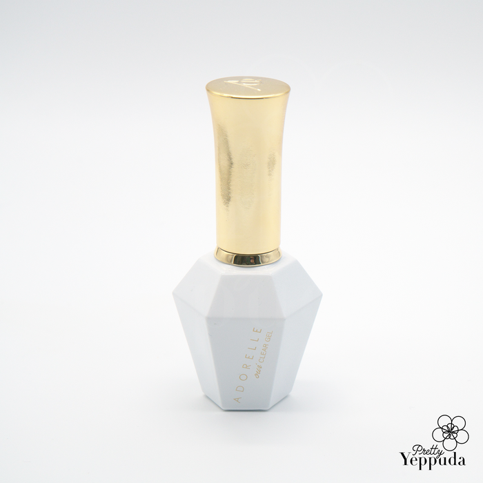 Elegant white hexagonal nail polish bottle with gold cap, featuring Adorelle Oui Clear 16ml, a premium transparent nail lacquer for a glossy, professional manicure finish. Luxurious packaging design showcases the high-quality formula inside.