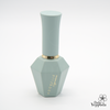 Elegant sage green nail polish bottle from ADORELLE Romantic Vintage collection, featuring a geometric faceted base and sleek cylindrical top with gold accent ring. The bottle showcases the brand name in delicate gold lettering, embodying a sophisticated and timeless aesthetic perfect for romantic, vintage-inspired manicures.