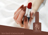 Alluring lipstick encased in a chic, modern container from the BESSIE Bitter Sweet Collection, featuring a rich, indulgent chocolate-inspired hue that effortlessly complements any autumn-inspired makeup look. This captivating product seamlessly blends BESSIE's signature style and quality, promising a haute-couture cosmetic experience.