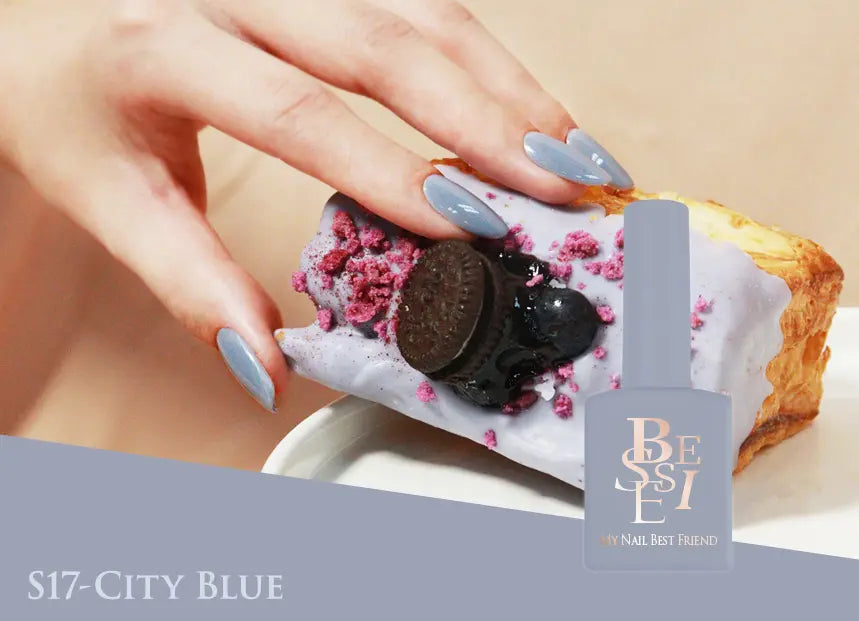 Colorful manicured nails elegantly hold a delectable dessert, showcasing the rich and vibrant tones of BESSIE's Bitter Sweet Collection. The pastry's soft and sweet interior is beautifully complemented by the pastel blue nail polish, creating a visually captivating and stylish presentation that embodies BESSIE's refined and trendsetting brand aesthetic.