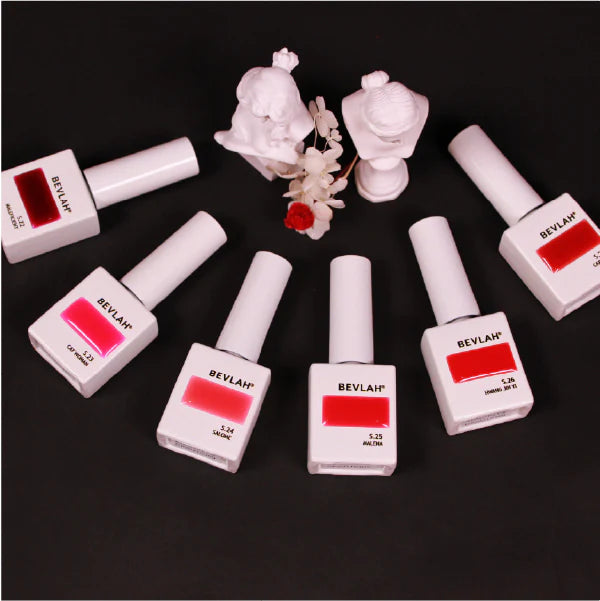 A collection of BEVLAH branded gel nail polishes in various shades of red, displayed on a dark background. The products include bottles of red gel polish, applicators, and decorative elements, showcasing the brand's Crazy Red collection of bold, vibrant red nail lacquers.