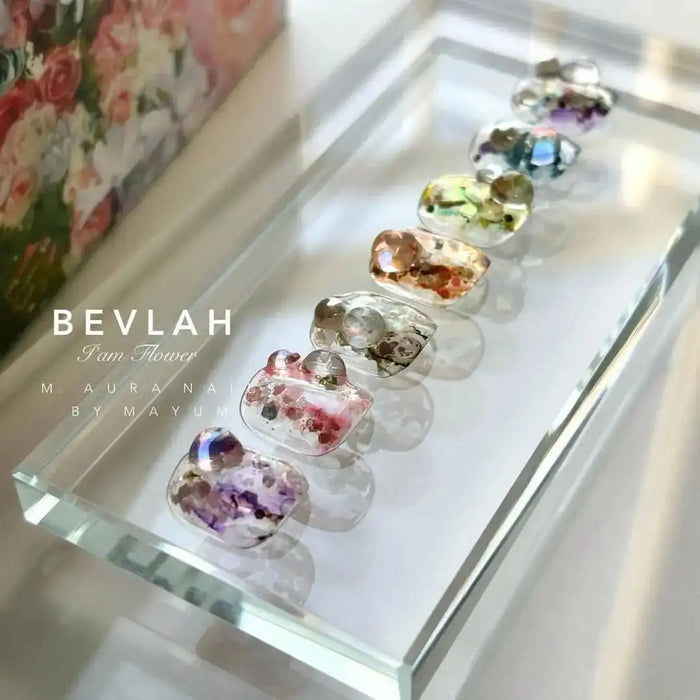 A vibrant and enchanting array of handcrafted flower-infused gels, meticulously blended with a touch of glitter to create a dazzling and unique Petal Collection by the renowned BEVLAH brand. Each piece showcases the natural beauty and variety of over 70 real flowers, resulting in a one-of-a-kind product that celebrates the diversity and charm of nature.