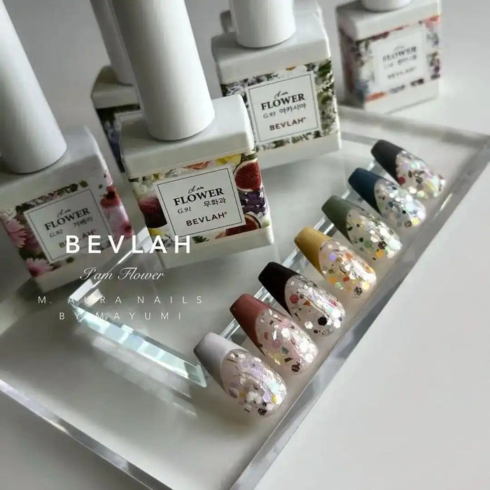 Vibrant and eye-catching gel nail product display showcasing the BEVLAH "I Am Flower" collection, featuring a variety of floral-infused gels and polishes in a visually appealing and cohesive presentation. The assortment highlights the brand's commitment to using real flowers and glitters in their formulations, creating a dazzling and unique nail care experience for their customers.