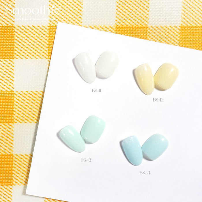 Four pastel nail color swatches from the Smoothie Fresh Pastel Tone Collection by BY MUSE, displayed on a white card against a yellow checkered background. The colors include BS 41 White Sand, BS 42 Forsythia, BS 43 Surf Crest, and BS 44 Powder Blue.