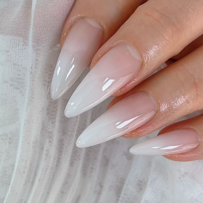 Close-up of long, almond-shaped nails featuring a delicate ombre design created with NAILBAYO DOI Aube #1. The gradient transitions smoothly from a soft pink at the base to a translucent white at the tips, giving a natural and elegant look.