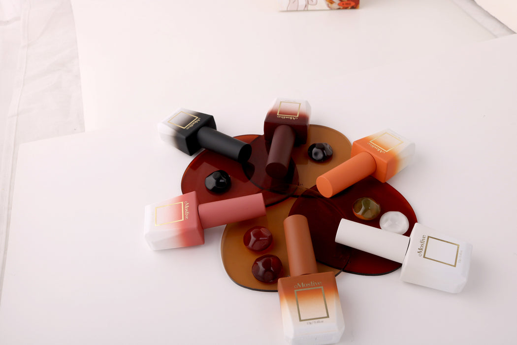 Colorful and assorted nail polish bottles, caps, and applicators in shades of red, orange, and brown, arranged on a white background, showcasing the diverse products in the Mostive Midnight Latte Collection (MC017-022) by Mostive, a Shopify nail care brand offering gel nail polishes that require curing with a UV/LED lamp.