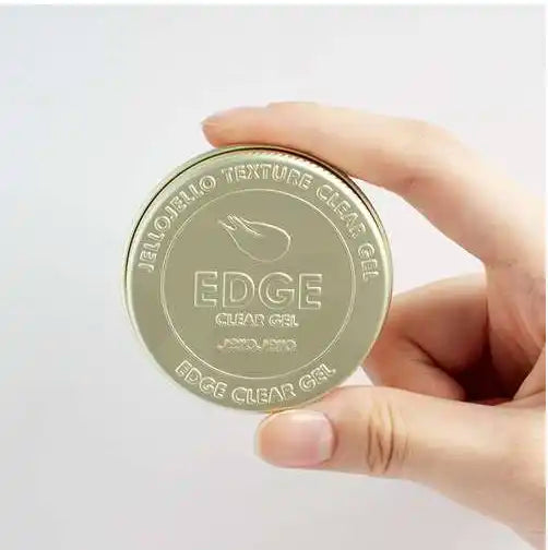 A close-up image of a metallic jar lid with the "EDGE CLEAR GEL" product name and branding prominently displayed, showcasing the high-quality and smooth texture of this chrome-focused hair styling gel for structure and definition.