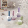 Eight vibrant gel nail polish bottles in pastel winter colors, including soft blue, pink, lavender, and green, displayed against a snowy, winter backdrop with pine cones and snowflakes, perfectly capturing the essence of the JIN.B Winter Story Collection. This carefully curated set offers a diverse range of hues to complement your seasonal designs and inspire a cozy, winter-inspired aesthetic.