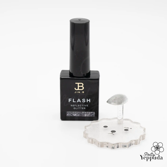 JIN.B Flash Reflective Glitter nail polish bottle in sleek black packaging, showcasing the product name and brand logo. Accompanied by a transparent, flower-shaped nail art palette for precise application. The image highlights the professional quality and versatility of this UV/LED curable glitter polish for stunning manicures.