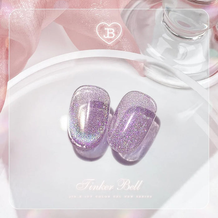 A pair of shimmering, lavender-colored cat-eye gel manicure sets resting on a white plate, set against a soft, pink-toned background, showcasing the mesmerizing and enchanting nature of Jin.B's Tinker Bell collection of magical nail products.