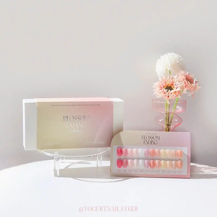 Twelve vibrant, natural-looking gel nail polish colors from the Yogurt Blossom Ending Collection, displayed in a branded packaging and accompanying floral accents, creating an inviting and visually appealing product presentation.