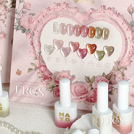 The image displays a collection of magnetic gel nail polish bottles from the MAYO Eros Collection, featuring a variety of vibrant and shimmery shades inspired by the goddess of love. The product showcases a heart-shaped color palette, surrounded by delicate pink floral arrangements, creating an elegant and romantic ambiance.