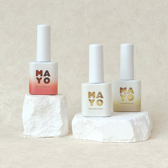 Three bottles of MAYO Eros Collection gel nail polish, featuring a range of shades inspired by the goddess of love, including delicate pinks, fiery oranges, serene greens, and golden hues. The bottles are displayed on white marble-like pedestals, showcasing the premium quality and elegant design of the MAYO brand.