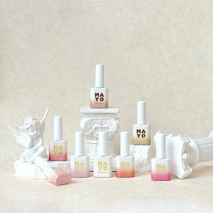 Assortment of colorful nail polish bottles and decorative elements on a soft, light-colored background, showcasing the MAYO Eros Collection of magnetic gel nail colors.