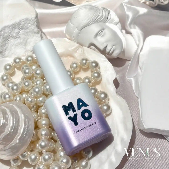 The image depicts a close-up of a bottle of MAYO Venus Collection 8-piece magnetic gel set, surrounded by pearls and a ceramic figurine reminiscent of the goddess of love. The product appears to be a high-quality, luxurious cosmetic item, emphasizing the brand's focus on quality, elegance, and inspiration drawn from Venus, the goddess of love.