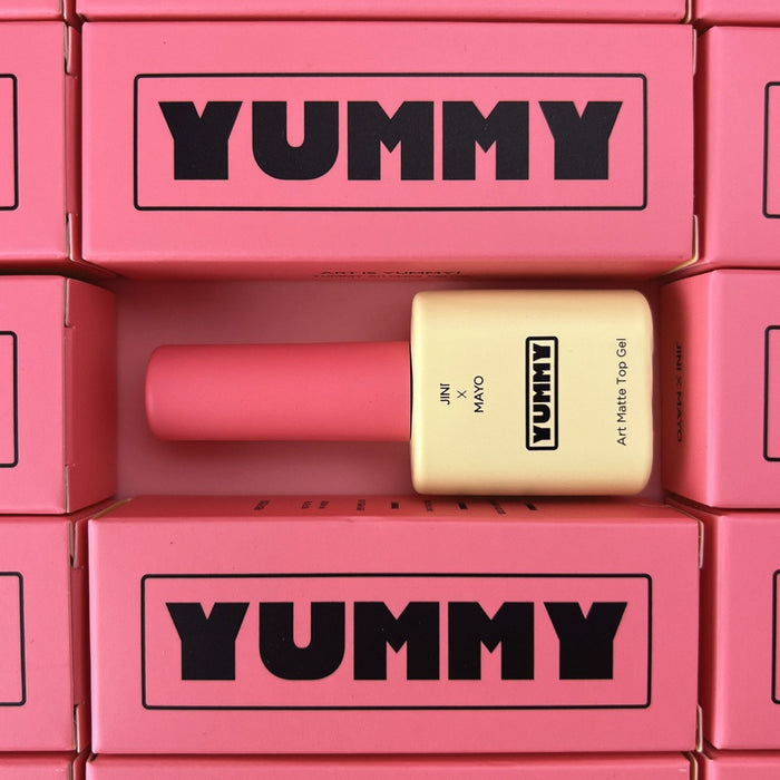 A top-down view of Yummy Art Matte Top Gel bottles arranged within a grid of pink branded boxes. The repetition of the 'YUMMY' logo creates a striking visual effect, emphasizing the brand's identity.