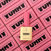 A top-down view of Yummy Art Matte Top Gel bottles arranged within a grid of pink branded boxes. The repetition of the 'YUMMY' logo creates a striking visual effect, emphasizing the brand's identity.