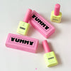 Multiple bottles of Yummy Art Matte Top Gel in yellow and pink packaging, displayed with their matching pink boxes labeled 'YUMMY.' The nail gel is positioned in an aesthetically pleasing arrangement on a light background.