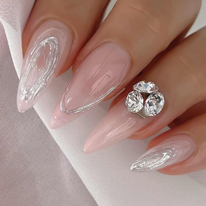 Elegant stiletto nails featuring delicate pink base with intricate clear swirl designs and sparkling rhinestone accents, showcasing the versatility and beauty of Nailbayo DOI Thick Gel for creating sophisticated Korean-inspired nail art styles