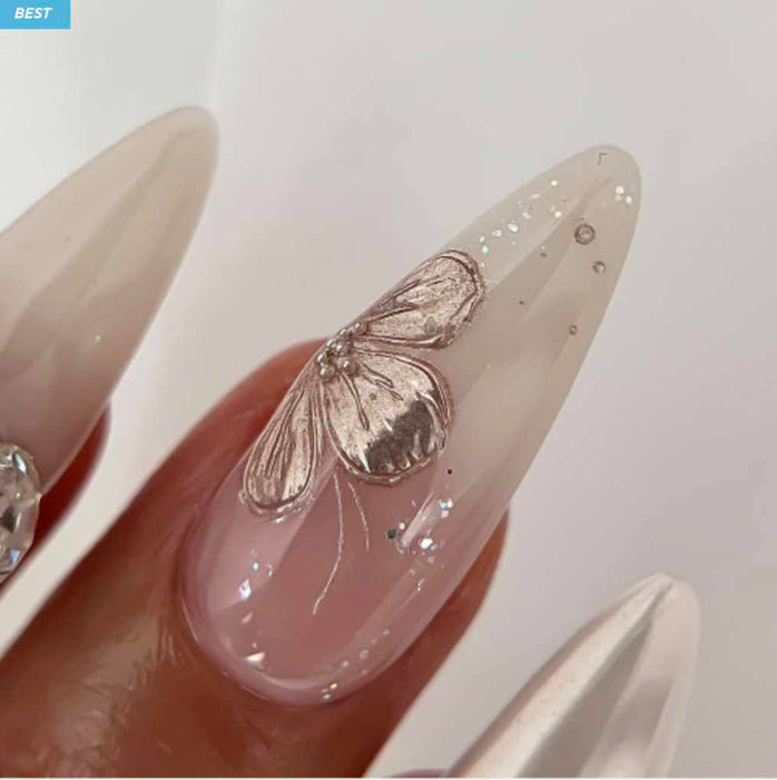 A close-up photograph of an elegant, beautifully manicured nail featuring a striking butterfly design in shimmering gold and pink hues. The nail polish appears to be a high-quality gel product from the renowned Korean nail brand NAILBAYO, as described in the product details. The intricate butterfly motif adds a touch of whimsical charm and glamour to this carefully crafted nail art.