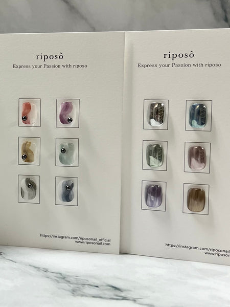 A set of 6 Riposo Metal Ink products in various metallic colors like silver, aqua blue, light green, rose pink, light purple, and reddish brown, displayed in a product catalog with samples showcasing the glossy finish achieved by using Riposo's top coat or powder gel, offering a unique and eye-catching alternative to traditional metal inks.