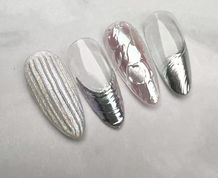 A set of stylish silver RIPOSO Nuance Grip Gel nails with intricate patterns and a glossy finish, showcasing the brand's innovative nail products designed to create beautiful nuanced nail designs. The nails are presented on a neutral background, highlighting the stunning metallic tones and attention to detail in the RIPOSO Nuance Grip Gel collection.