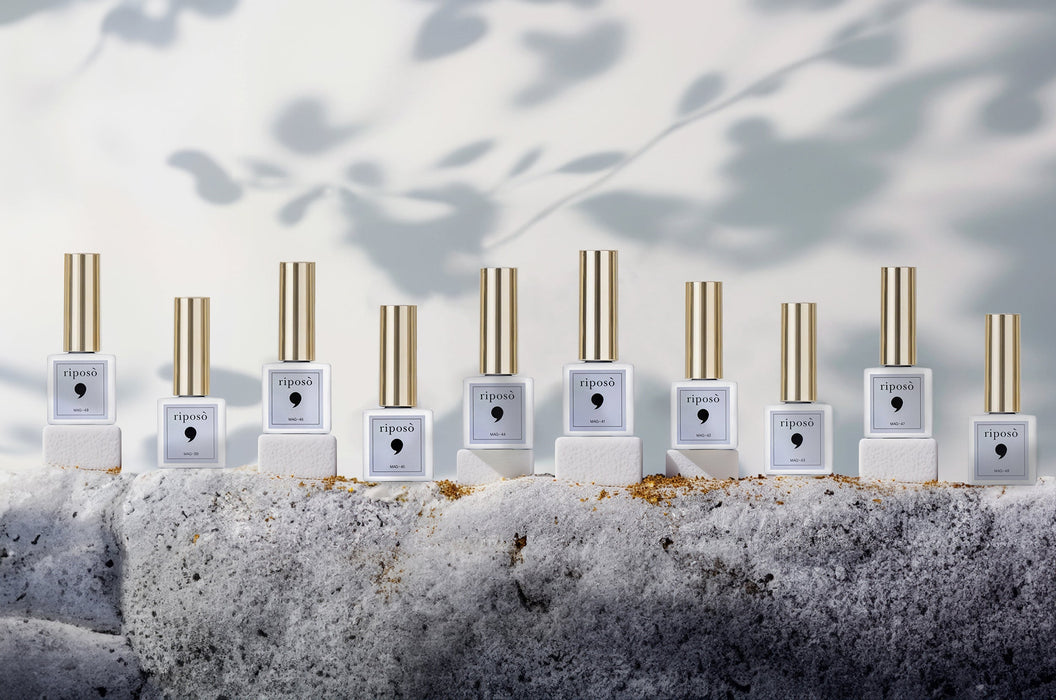 A collection of ten RIPOSO Pulling Jellybean nail polish bottles in a minimalist, modern arrangement, showcasing their sleek, white packaging with gold accents. The bottles are nestled in a bed of soft, powdery snow, creating a serene, winter-inspired scene that captures the essence of the , RIPOSO brand.