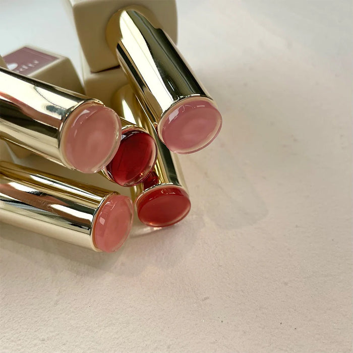 Assortment of colorful lipstick tubes in the LOVE LOVE SYRUP D SET, featuring a variety of nude, rosy, and mulled wine shades with a soft, transparent, and layerable formula for a customizable lip glow effect.