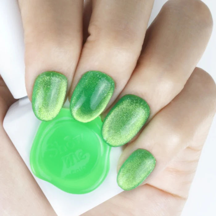 Close-up image of a person's hands showing vibrant green cateye nail polish from the "SHOW ME KOREA - Cooing Punch Cat Eye Gel Series" product line. The nail polish has a shimmery, textured appearance characteristic of cateye nail gels, effectively showcasing the bold, eye-catching colors of this nail care brand.