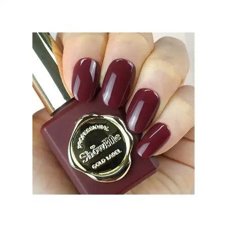 A close-up image of a hand holding a burgundy-colored nail polish bottle from the "Show Me Korea" brand's "Salon De Latte" collection. The nail polish bottle has a gold cap and label, showcasing the unique and vibrant color of this professional-grade, long-lasting gel nail polish.