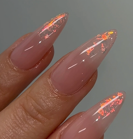 Peach sunset glitter nail polish with iridescent flakes adds a captivating, aurora-like shimmer to nails, complementing marble and stone nail art designs for a stunning, Nailbayo Shopify product.