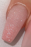 Detailed description of the Nailbayo Shushu glitter product image: The image shows a close-up view of a human hand with beautifully manicured nails painted with a fine, white glitter polish. The glitter appears to be evenly distributed across the nail surface, creating a dazzling, iridescent effect that catches the light. The overall impression is one of elegance, sophistication, and a touch of whimsy, perfectly capturing the essence of the Nailb