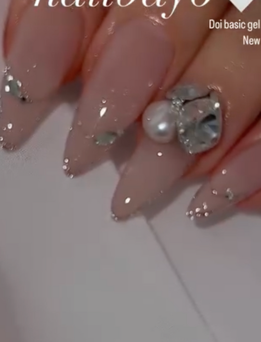 A close-up image of a fingernail coated in a shimmery, glittery gel polish. The nail polish has a light, iridescent finish with specks of silver glitter scattered across the surface, creating a dazzling effect. The image showcases the high-quality, shimmering Nailbayo Doi Tong gel product, a popular Korean nail art gel known for its exceptional sparkle and shine.