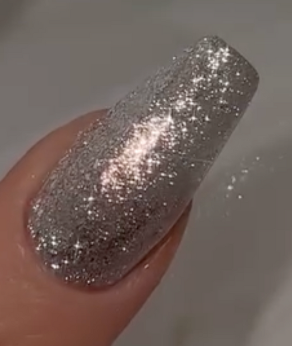 A close-up image of a finger with a sparkling silver nail polish, showcasing the vibrant and shimmering Nailbayo Doi Tong Gel by the renowned Korean nail artist Nailbayo, featuring a mesmerizing display of glitter and an opulent, glamorous aesthetic.