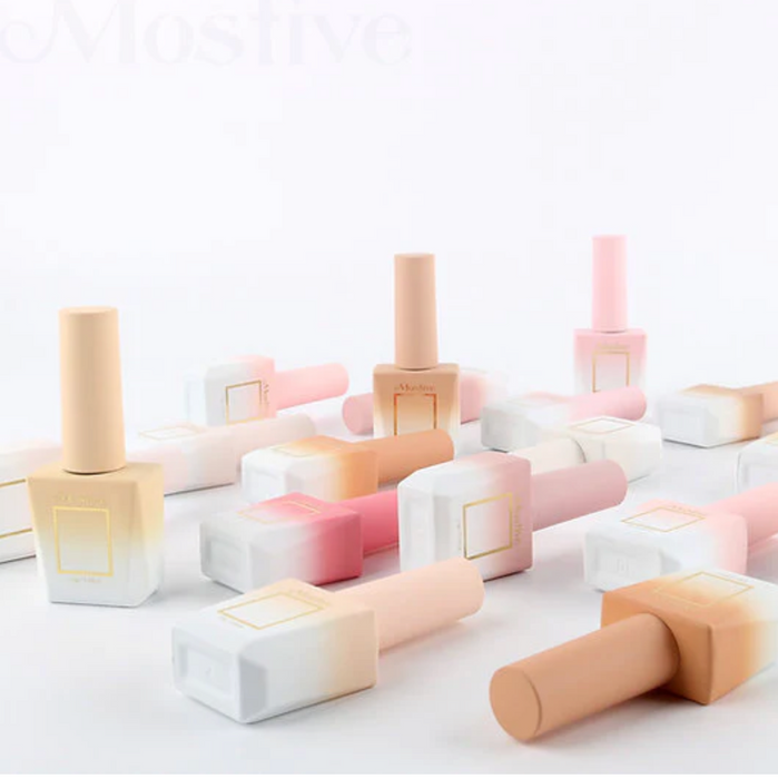 A diverse assortment of pastel-colored nail polish bottles and cosmetic products, arranged in a visually appealing and minimalist display. The image showcases the "Mostive I am your skin Collection (MCS031-40)" product line, featuring a variety of shades from oat white to rose purple, all presented in a clean and organized manner.