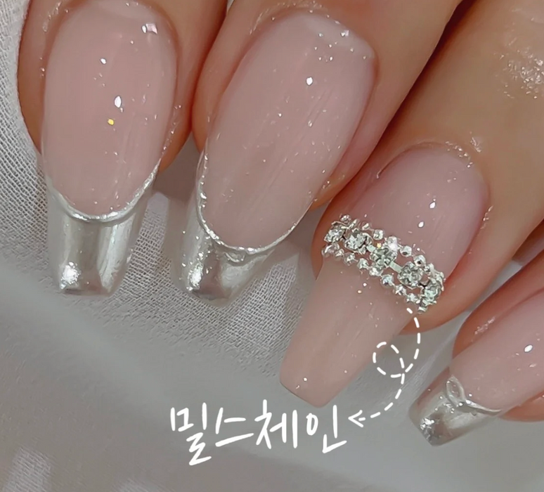 A delicate and glamorous manicure showcasing a shimmering nail polish hue, accentuated by a stunning rhinestone accent, perfect for the Nailbayo - Mils Chain Shopify product. The neutral base color and sparkling details create a sophisticated and fashionable look, ideal for the Nailbayo brand.