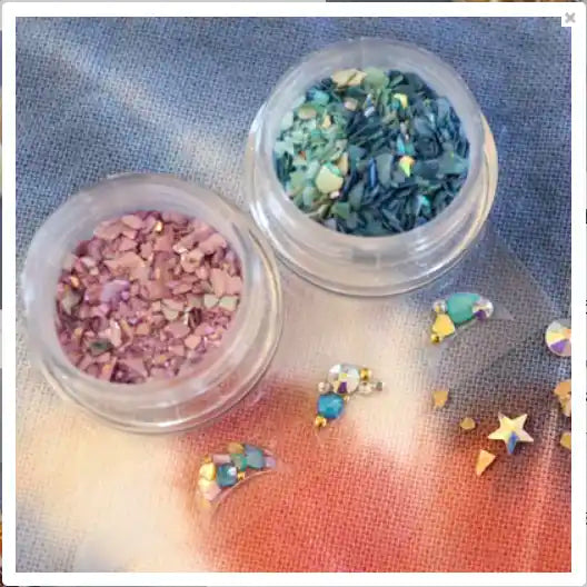 Colorful nail art supplies, including a variety of glitter and rhinestones in different shapes and hues, displayed on a textured surface.