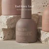 Close-up of three VALLA Earl Grey Leaf collection nail polish bottles in soft earth tones, positioned against a backdrop of natural stone. The image emphasizes the premium quality and subtle elegance of the gel colors.