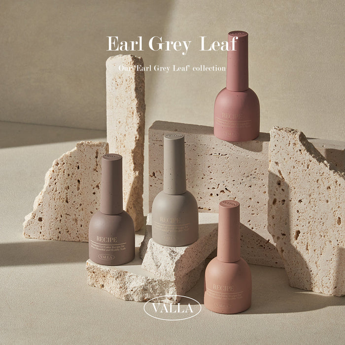 Artistic arrangement of VALLA Earl Grey Leaf nail polishes in muted earth tones, staged among geometric stone pieces. The setting highlights the sophisticated, natural-inspired hues of the collection.