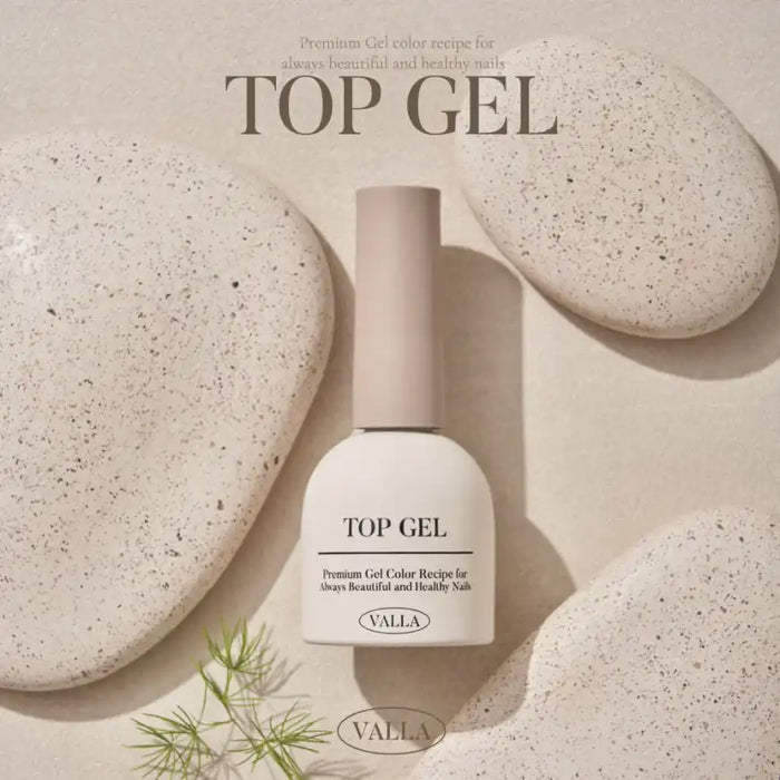 A close-up image of a white nail polish bottle labeled "VALLA TOP GEL" displayed on a textured beige background with natural elements, showcasing the premium gel formula designed for a shiny, non-wipe nail surface.