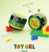 The image shows a Shopify product called "VALLA Toy Gel", which is a 3D clear clay gel that can be used for various creative purposes, such as 3D nail art. The product appears to be displayed with Lego-style blocks and other playful elements, highlighting its versatility and suitability for creative projects. The alt text for this image could be:

"VALLA Toy Gel - a 3D clear clay gel that can be rolled, squished, and sculpted for creative project