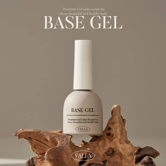 VALLA Base Gel nail polish bottle standing on a rugged, natural wood piece against a neutral brown background. The bottle is clearly labeled 'Base Gel' as part of VALLA's premium nail care line for healthy nails.