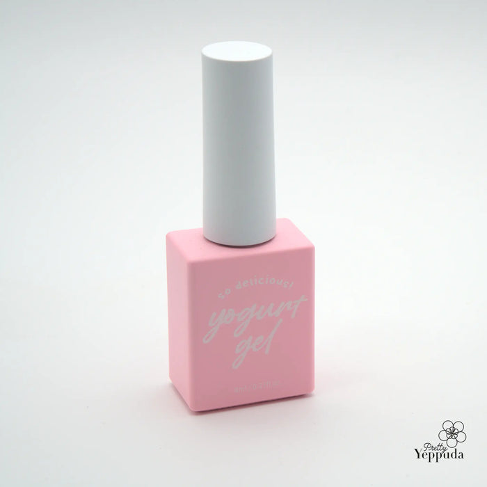 A vibrant pink nail polish bottle stands upright, featuring a minimalist white cap. The bottle's label displays the text "YOGURT gel" in a stylized cursive font, creating a delicate and feminine aesthetic. This product image showcases the simplicity and elegance of the Yogurt brand's nail care offerings, highlighting its commitment to high-quality, on-trend cosmetic solutions.