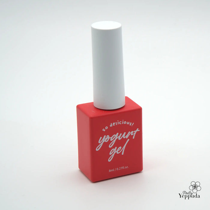 A bright red nail polish bottle with a white cap, prominently displaying the "yogurt gel" brand name and description "so delicious!" on the packaging. The minimalist design and stark contrast between the red and white colors create a visually appealing and eye-catching product display.