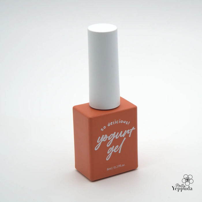 A vibrant, orange-colored nail polish bottle with a white cap, featuring the text "so delicious! yogurt gel" printed on the container, showcasing a high-quality, rich, and indulgent nail care product from the Yippuda brand.