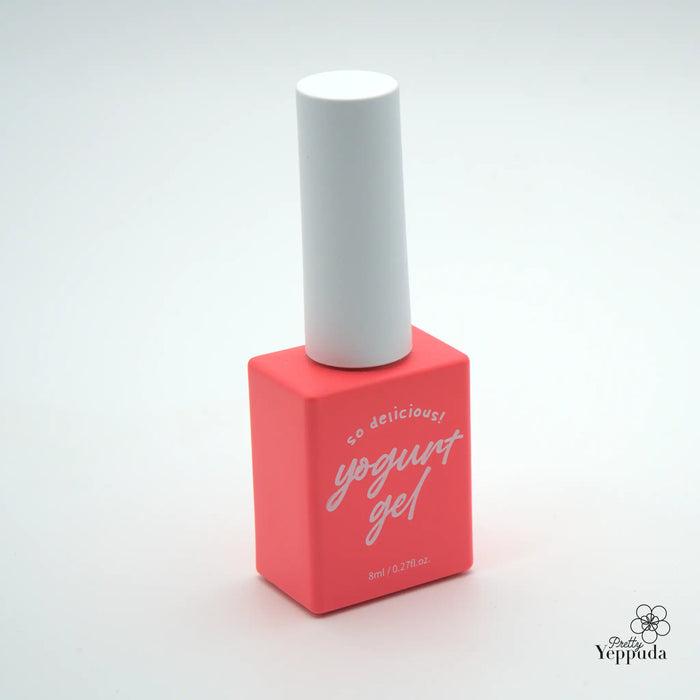 The image depicts a coral red nail polish bottle with white text on it. The bottle has a simple, minimalist design, featuring a cylindrical shape with a white cap. This appears to be a Yogurt-branded nail gel product, offering a wide range of 90 colors to choose from.