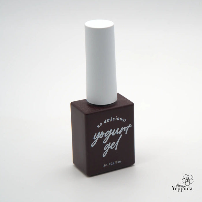 A minimalist and visually appealing image of a yogurt-themed product, likely a nail polish or gel, with a clean and modern design. The simple white bottle on a dark brown base creates a sleek and sophisticated look, emphasizing the "yogurt" branding prominently displayed. This image effectively showcases the product's essence and could be a valuable asset for Shopify marketing and e-commerce purposes.