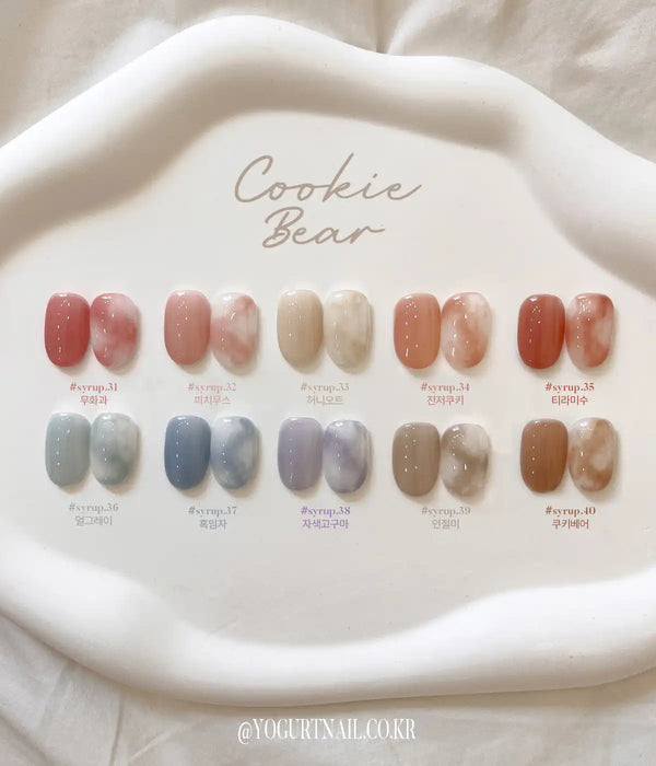 Colorful gel nail polish collection featuring warm and muted shades, with a variety of colors displayed on a white plate with the "Cookie Bear" branding.