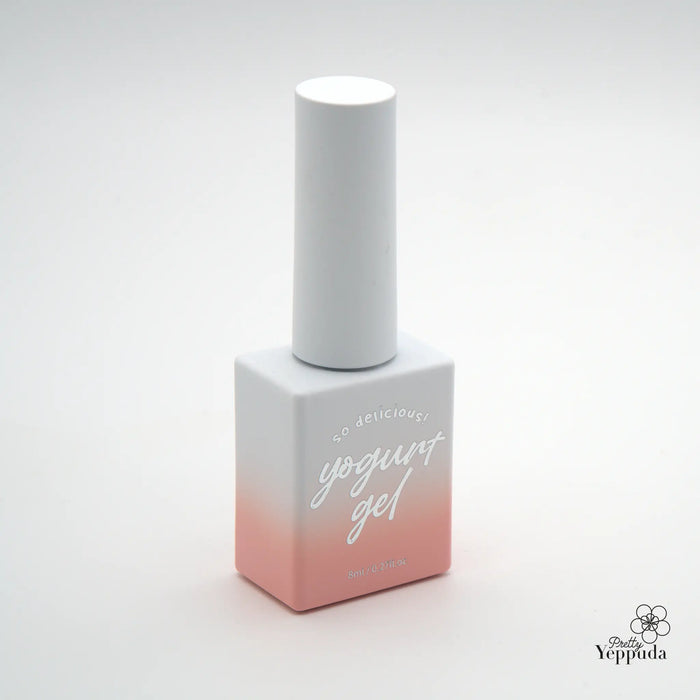 A delicate, pink-toned nail gel bottle with the brand name "Yogurt" prominently displayed in cursive script, situated on a minimalist white background.